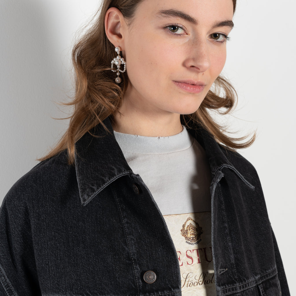 The Denim jacket by Acne Studios is crafted from non stretch denim in a black wash. Cut to a relaxed unisex fit with dropped shoulders and hip length