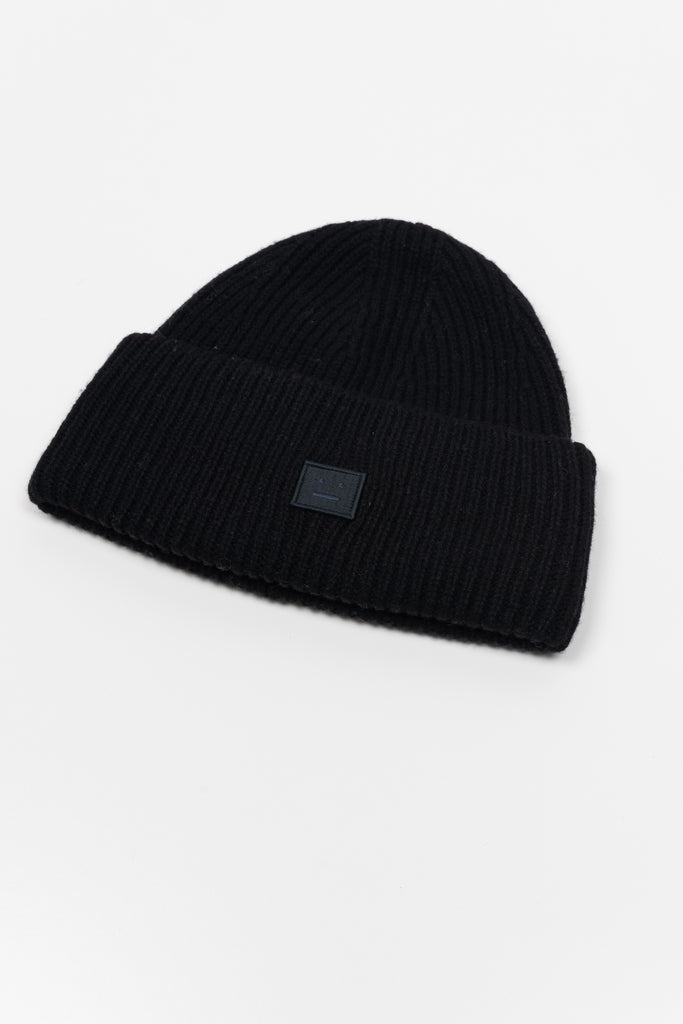 The Small Face Logo Beanie by Acne Studios features a small embroidered face logo patch and ribbed detailing, crafted from chunky wool.