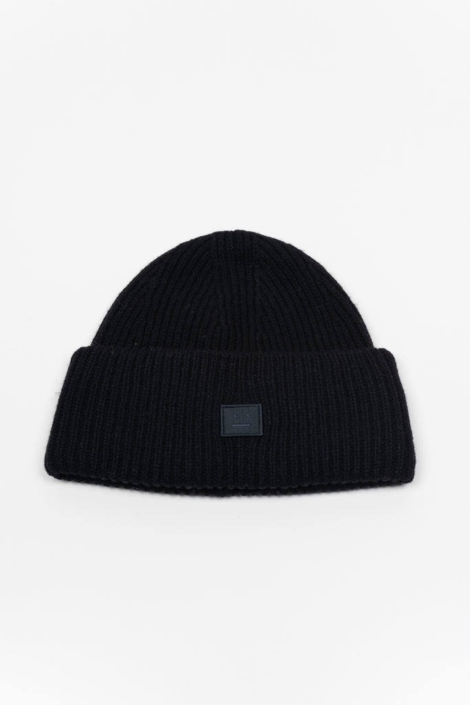 The Small Face Logo Beanie by Acne Studios features a small embroidered face logo patch and ribbed detailing, crafted from chunky wool.