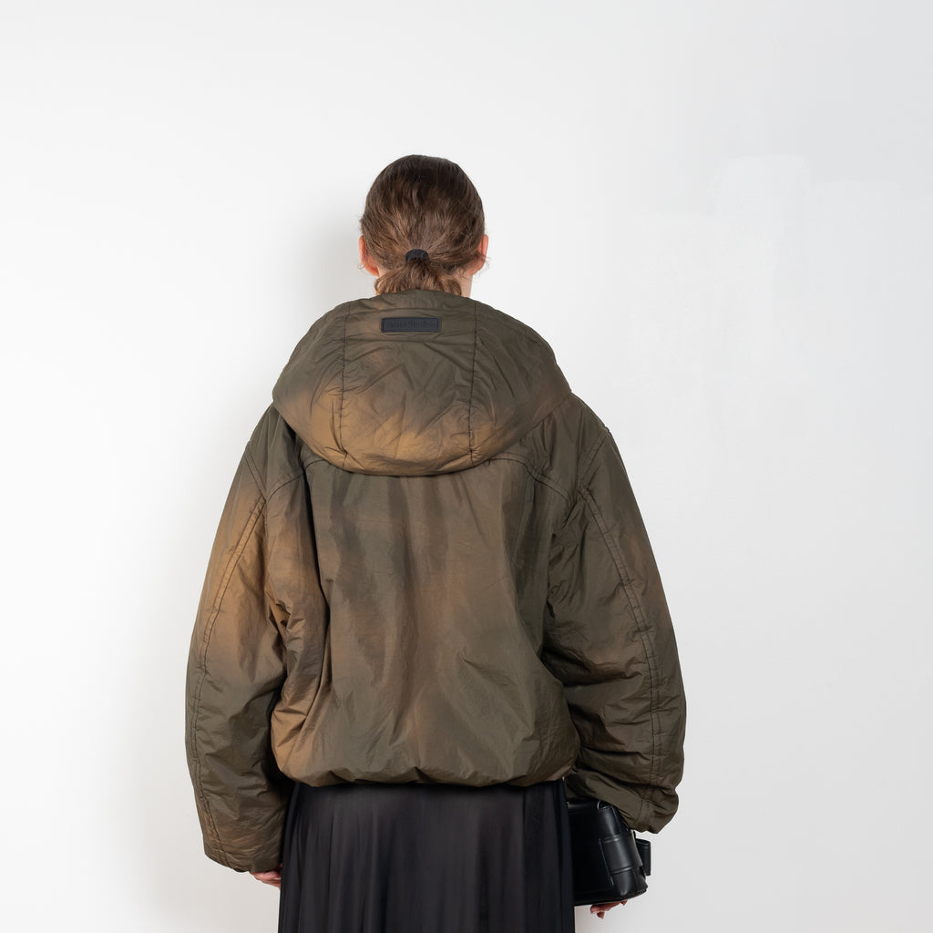 The Hooded Puffed Jacket by Acne Studios has a distinct coated finish crafted from water-repellant nylon