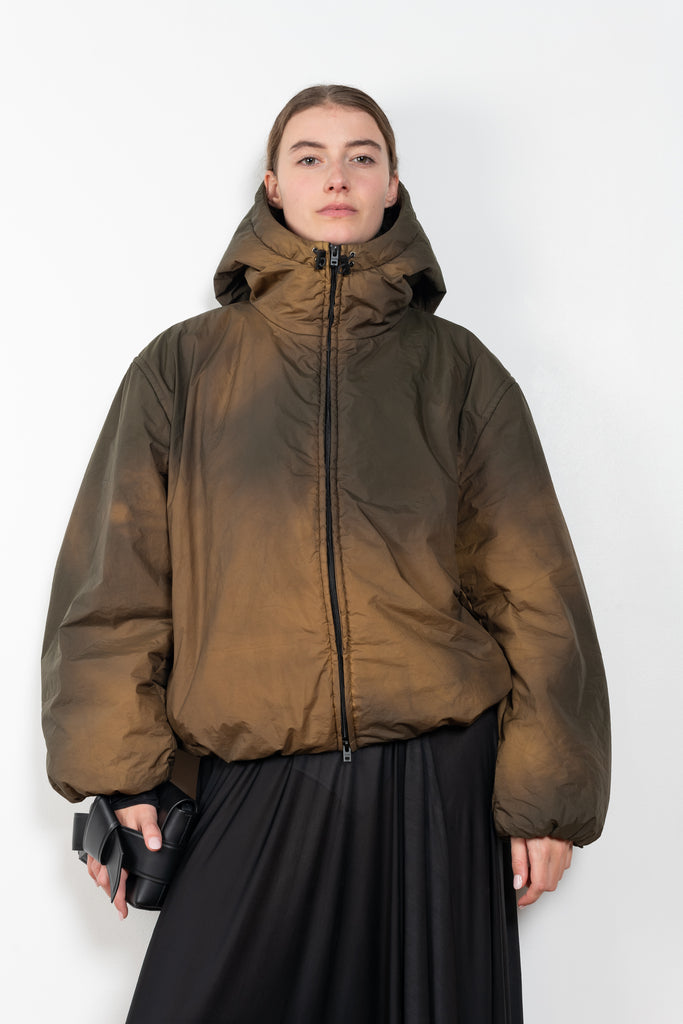 The Hooded Puffed Jacket by Acne Studios has a distinct coated finish crafted from water-repellant nylon