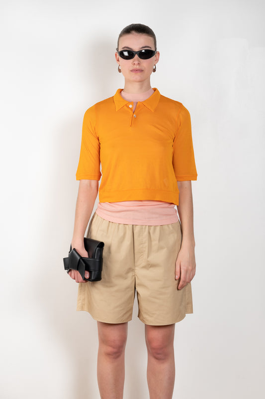 The Gauze Polo by Auralee is a cropped polo top in a vibrant orange sheer cotton jersey