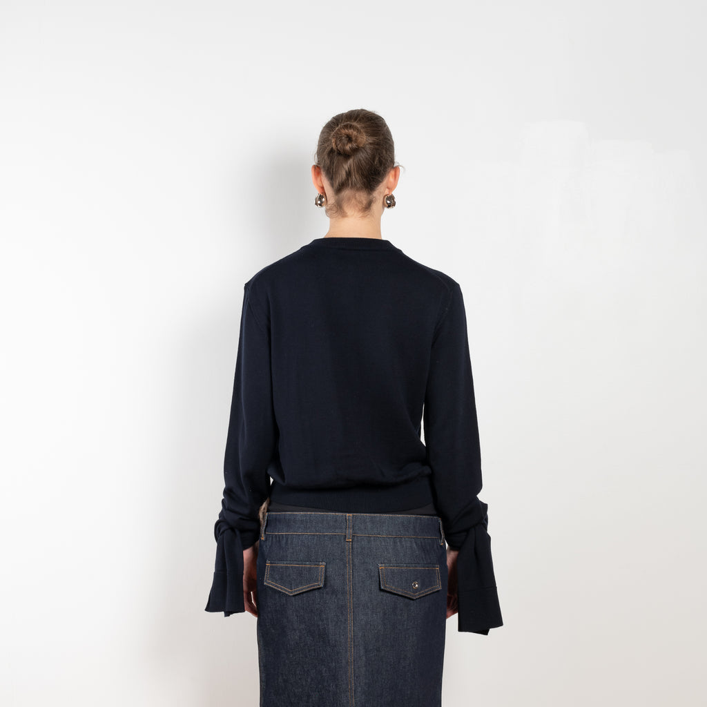 Knotted Sleeved Cardigan by Coperni is a navy cotton cardigan with extra long sleeves which are meant to be tied up in a knot