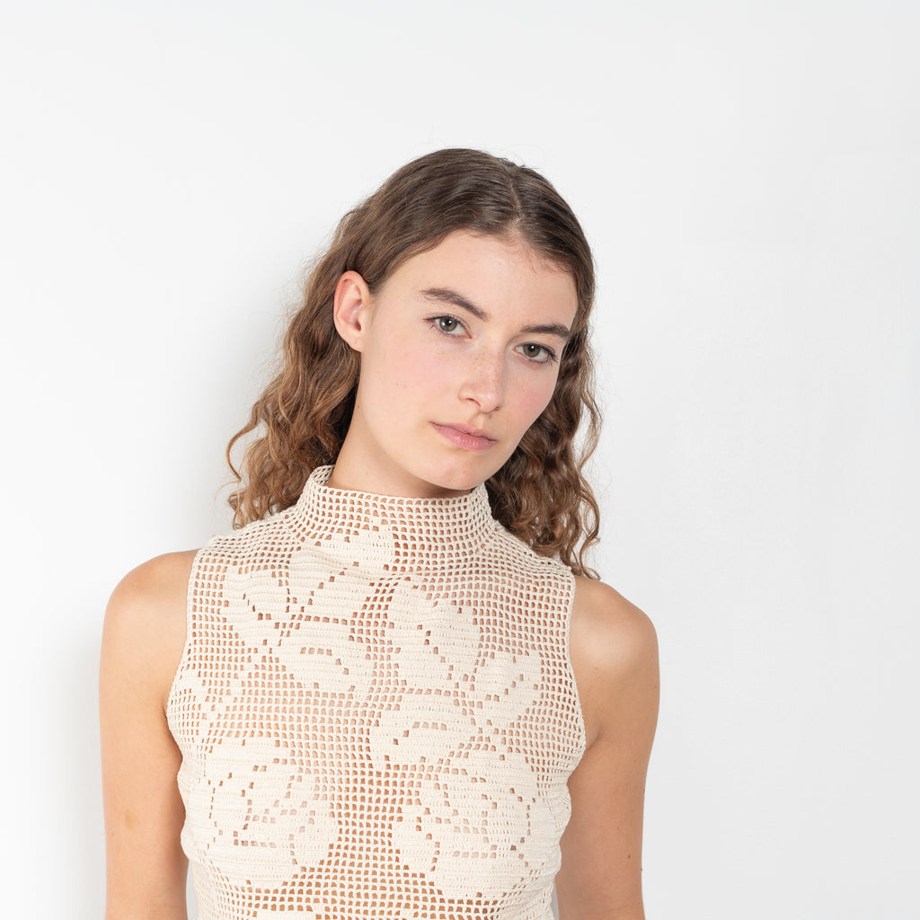 The Crochet Lace Top by Magda Butrym is a cropped top with a high neck and an all-over floral design in traditional Polish crochet technique