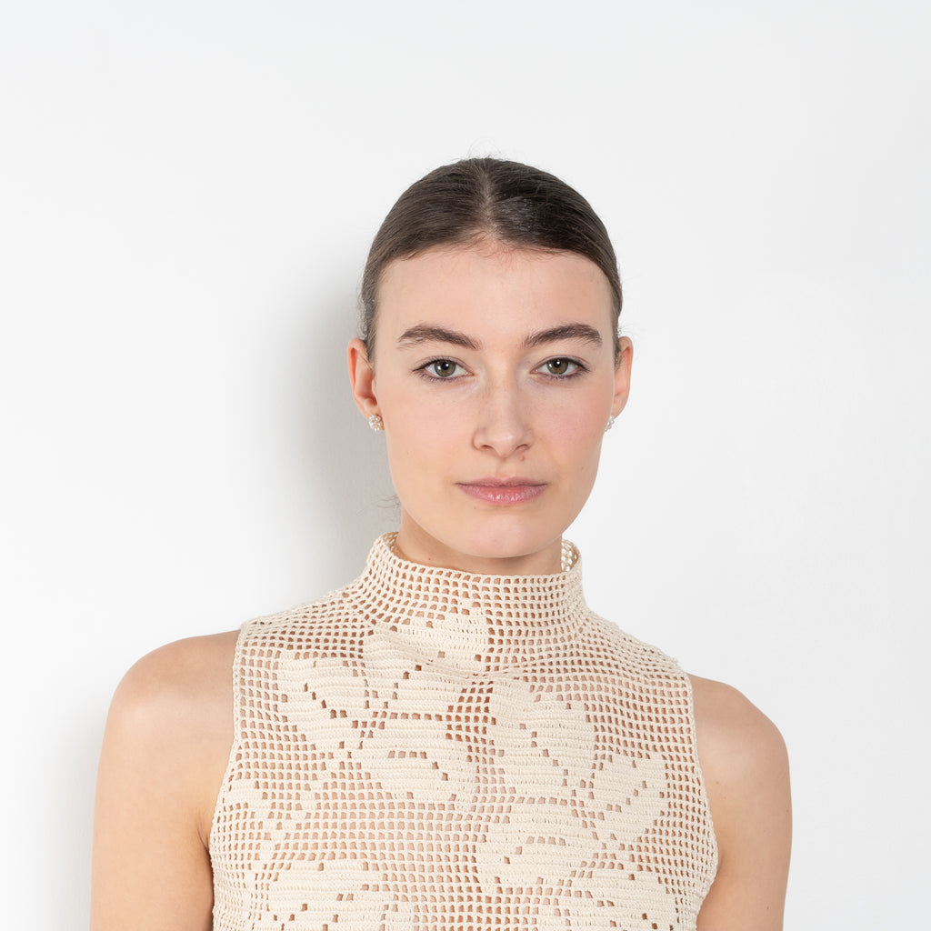 The Crochet Lace Top by Magda Butrym is a cropped top with a high neck and an all-over floral design in traditional Polish crochet technique