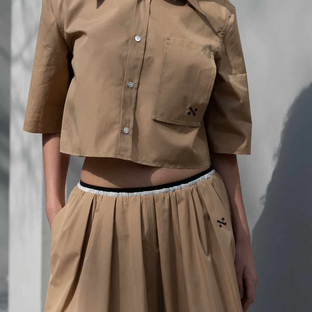 The Shortcut Shirt by Nackiye is a crop shirt with pointy collar and faux front pockets. 