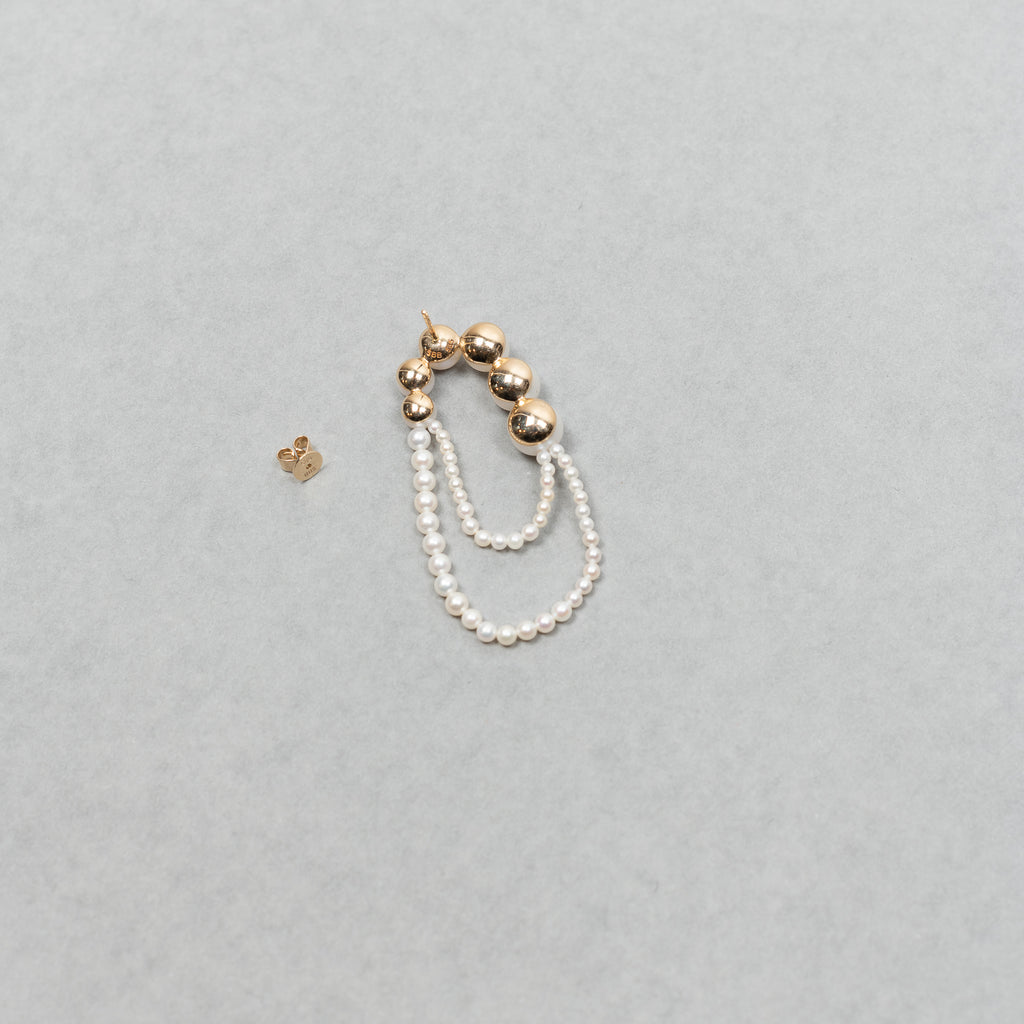 The motif of Bille Brahe's iconic Peggy wrapped to nest around one's ear appears on the Embrassée de Perle Earring, designed as a graduation of freshwater pearls