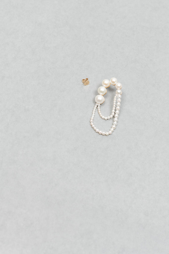 The motif of Bille Brahe's iconic Peggy wrapped to nest around one's ear appears on the Embrassée de Perle Earring, designed as a graduation of freshwater pearls