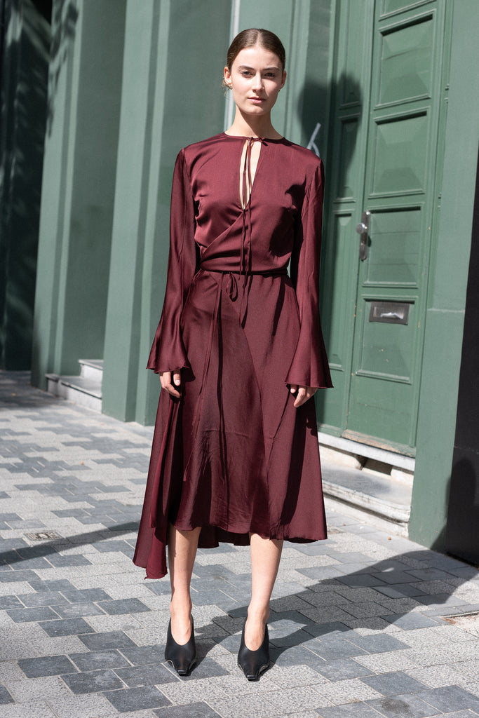 The Satin Dress 776 by ACNE STUDIOS has flared long sleeves, a side slit and asymmetric hem and closes with wrap tie ribbons at the waist