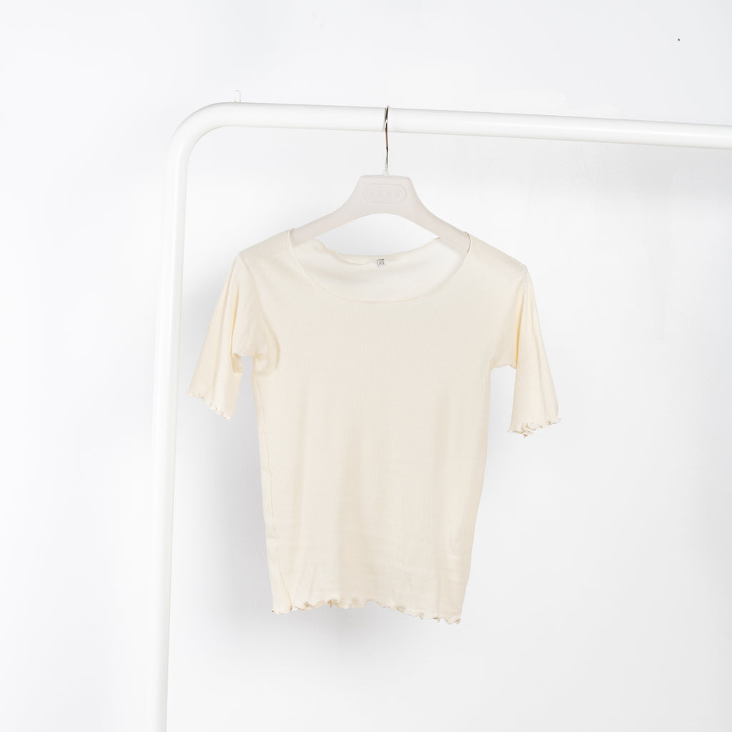 The Pama 3/4 Sleeve Tee by Baserange is a fitted cotton ribbed tee with exposed seams and lettuce edge details at hem and cuffs