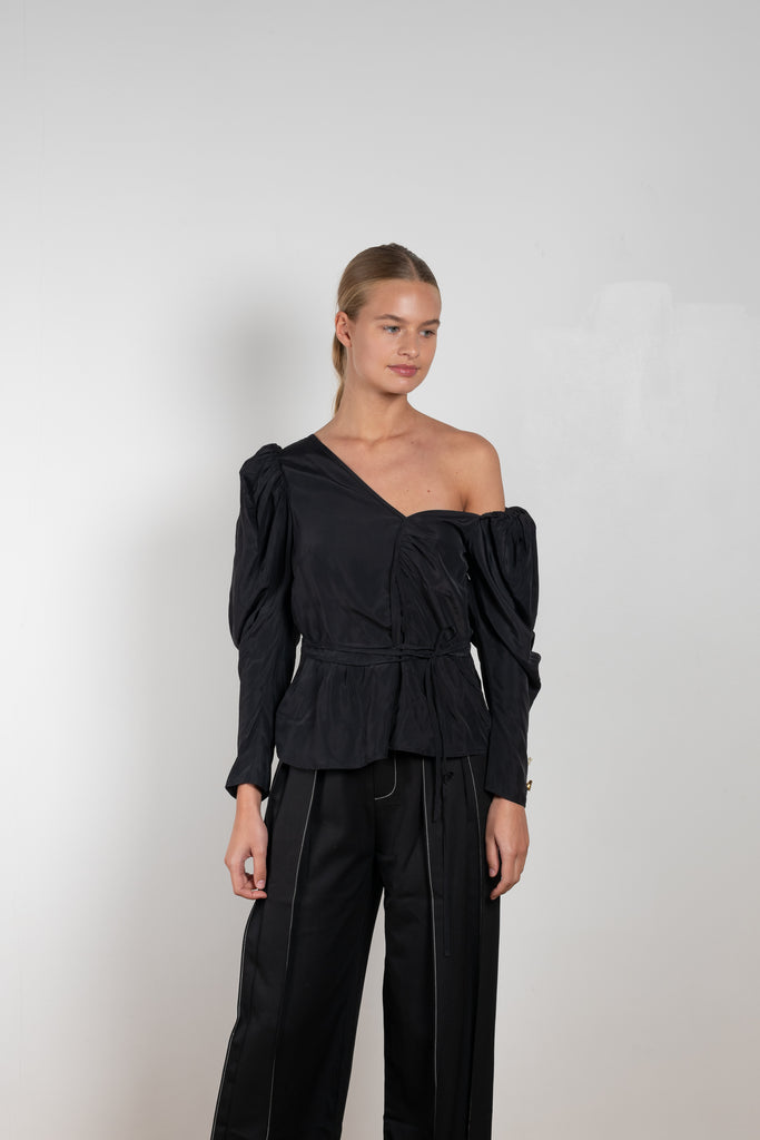 The Fiona Top by Rejina Pyo is a one-shoulder top with long puff sleeves, a tie detail to cinch the waist and exaggerated cuffs