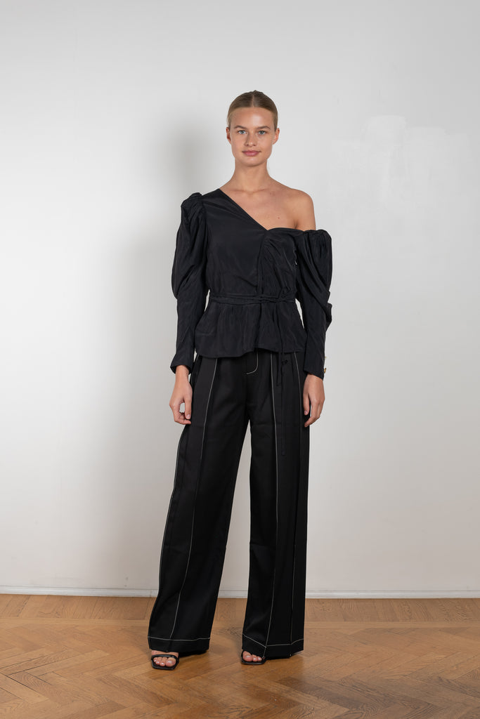 The Fiona Top by Rejina Pyo is a one-shoulder top with long puff sleeves, a tie detail to cinch the waist and exaggerated cuffs