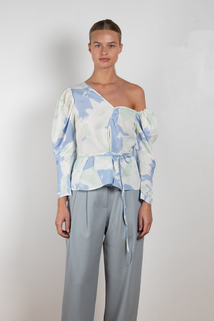 The Fiona Top by Rejina Pyo is a one-shoulder top with long puff sleeves, a tie detail to cinch the waist and exaggerated cuffs