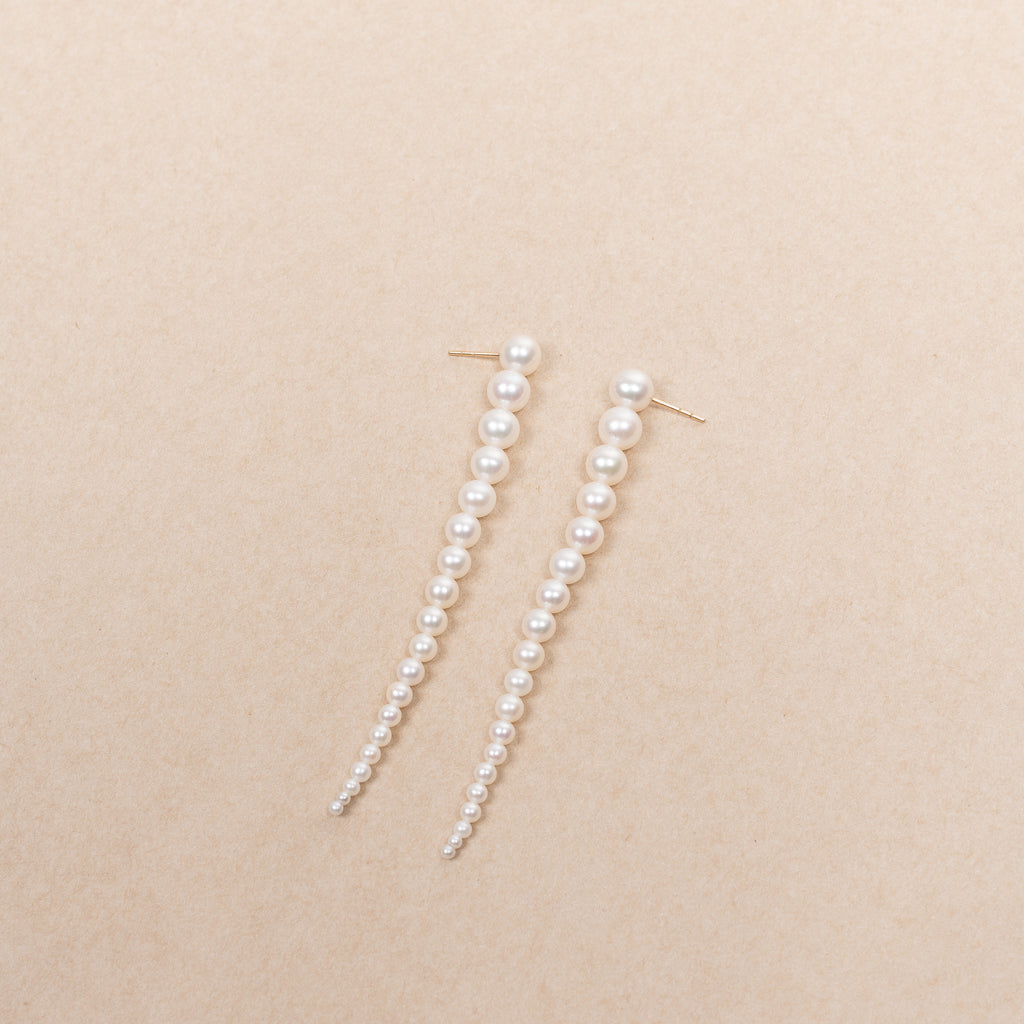 The Sienna Grand Earrings by Sophie Bille Brahe are a stunning and dramatic pair of earrings crafted in 14K yellow gold and white freshwater pearls graduating in size, which elegantly drop down