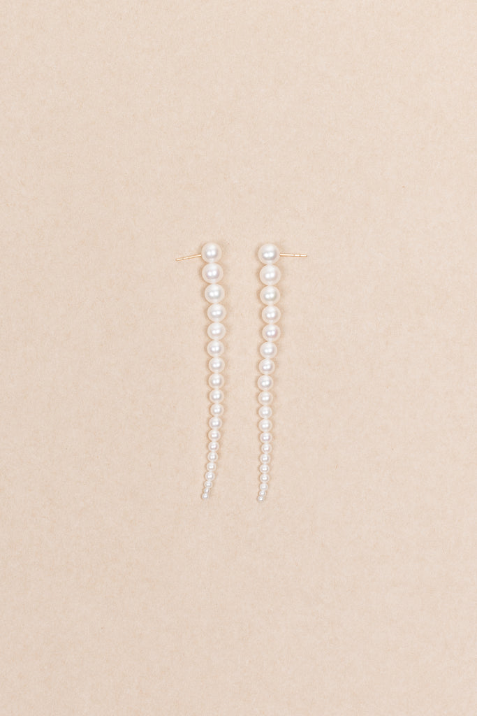 The Sienna Grand Earrings by Sophie Bille Brahe are a stunning and dramatic pair of earrings crafted in 14K yellow gold and white freshwater pearls graduating in size, which elegantly drop down