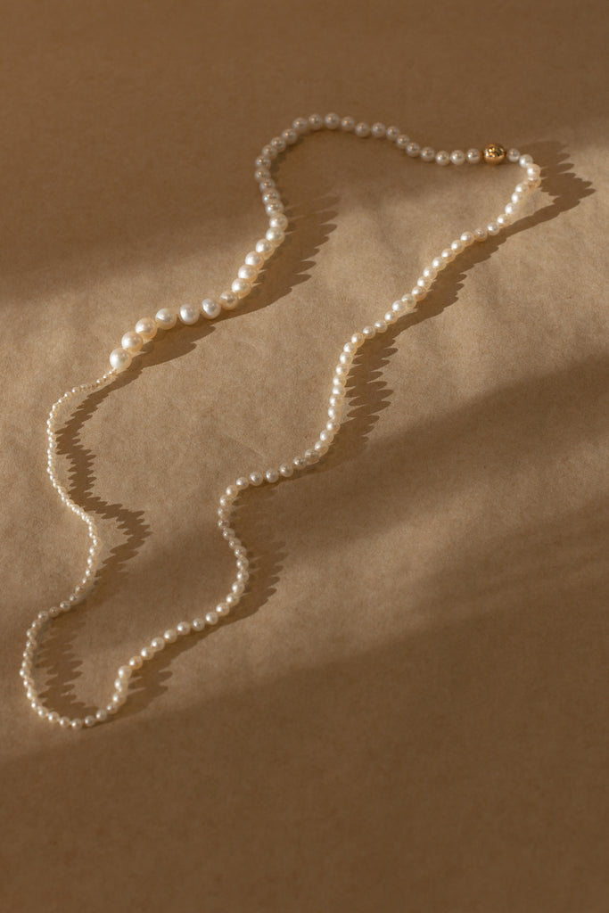 The Petite Peggy Perle Necklace is a longer version of the classic Petite Peggy Necklace with graduating sized Freshwater Pearls on an ancient Gold Lock